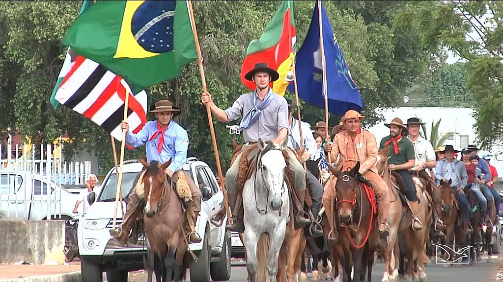 men on the street riding horses, wearing Gaucho hats, and holding their country flags