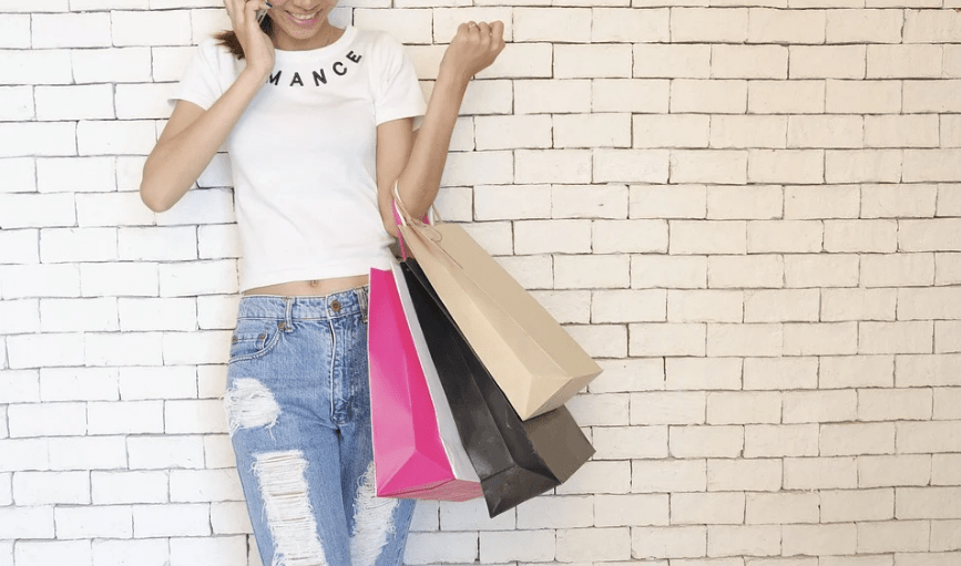 woman, shopping bags, white brick wall